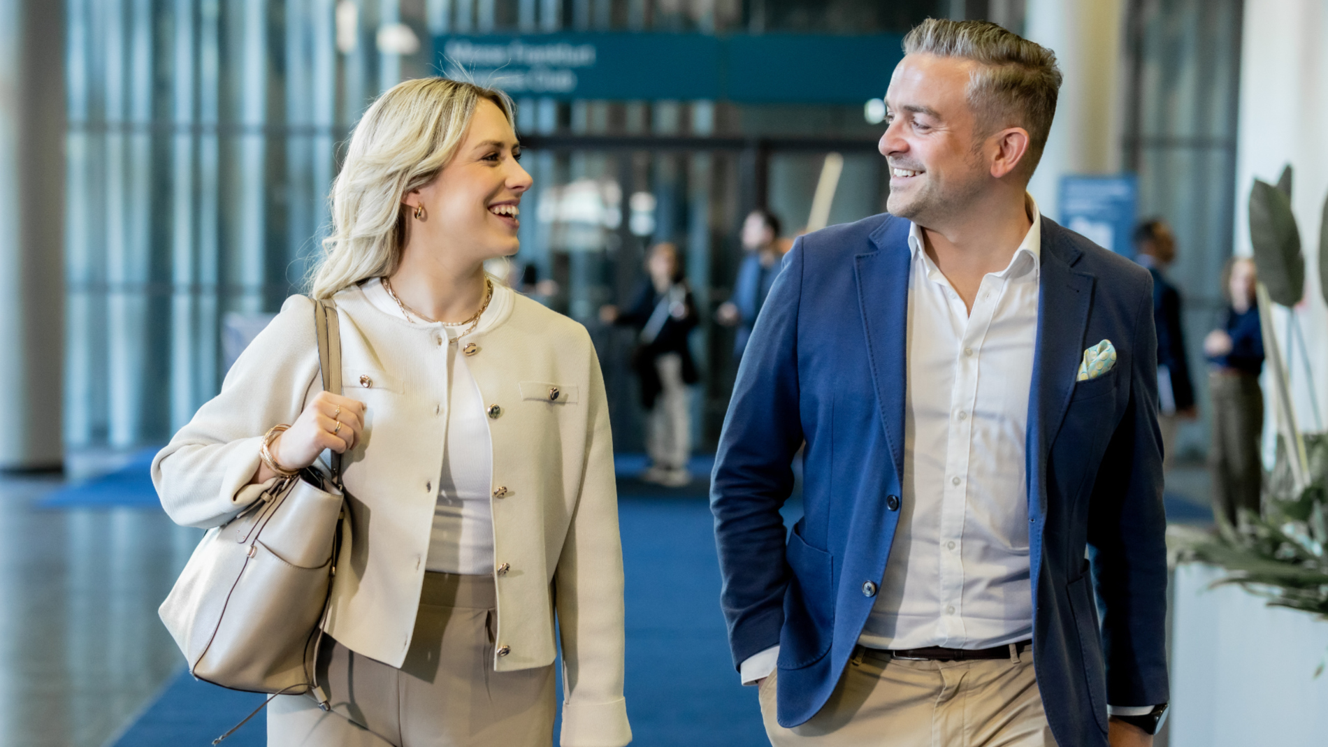 A man and a woman are walking in front of the Business Club