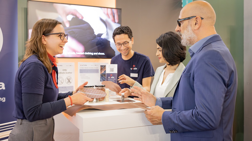 Besucher und Aussteller sprechen an einem Messestand über innovative textile Materialien